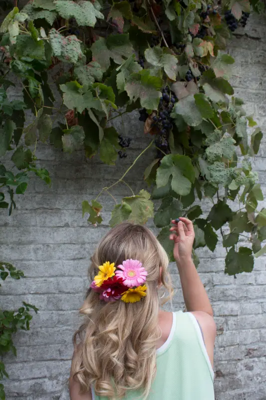 Kind met bloemen bij een muur met klimop